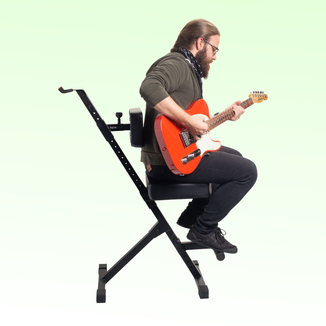 Person playing an electric guitar on a black adjustable chair against a light green background
