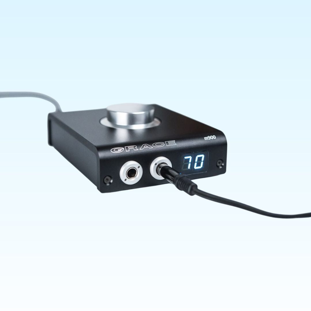 Angled front view of Grace Design m900 DAC Headphone Amplifier with cables attached on blue background