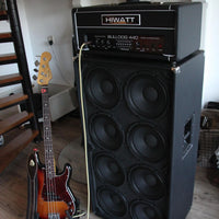 Angled view of Hiwatt Bulldog 440 Bass Amplifier Head on top of speaker cab with bass guitar beside it