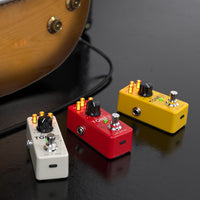 IK Multimedia TONEX One Brown Sound Pedals in Yellow, Red, and White on black surface with guitar in the background