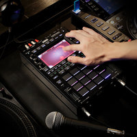 Angled top view of hand playing with Korg KAOSS Replay Dynamic Effects / Sampler on dark surface with other equipment around