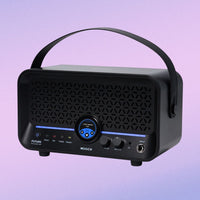 Black portable speaker with handle on a gradient purple background