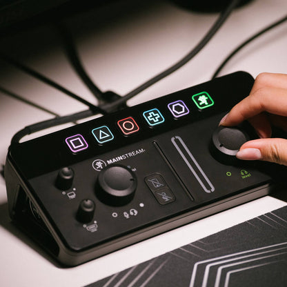 Angled view of hand adjusting the knob of Mackie MainStream Live Streaming and Video Capture Interface on studio desk