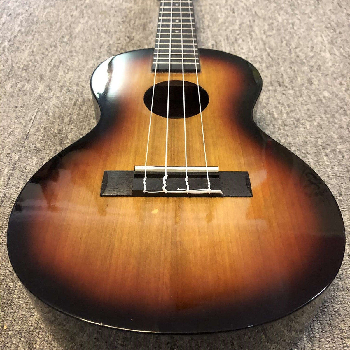 Angled close up view of Mahalo MJ4 Java Series Baritone Ukulele 3 Tone Sunburst on beige carpet