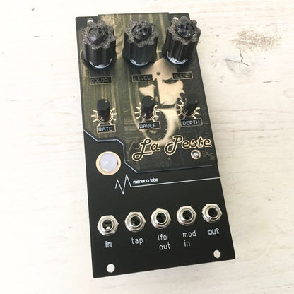 Angled view of Maneco Labs La Peste Fuzz Module on light wood surface