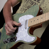Person playing a green electric guitar with a blurred background