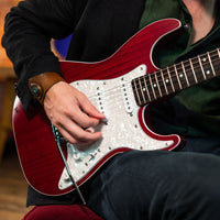 Person playing a red electric guitar with a blurred background