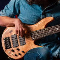 Person playing a bass guitar with a close-up on the instrument and hands.