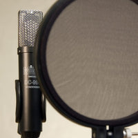 Milab DC-96C Single on stand in the background with pop filter on foreground with light amber background