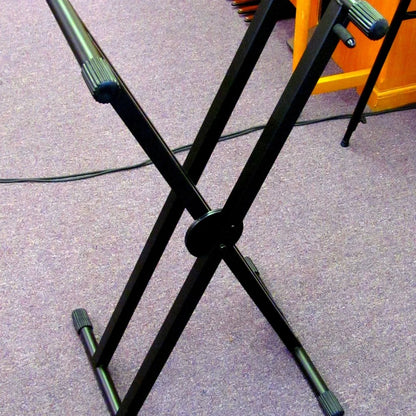 Angled view of On-Stage ERGO-LOK Double-X Keyboard Stand with Welded Construction on purple carpet in studio