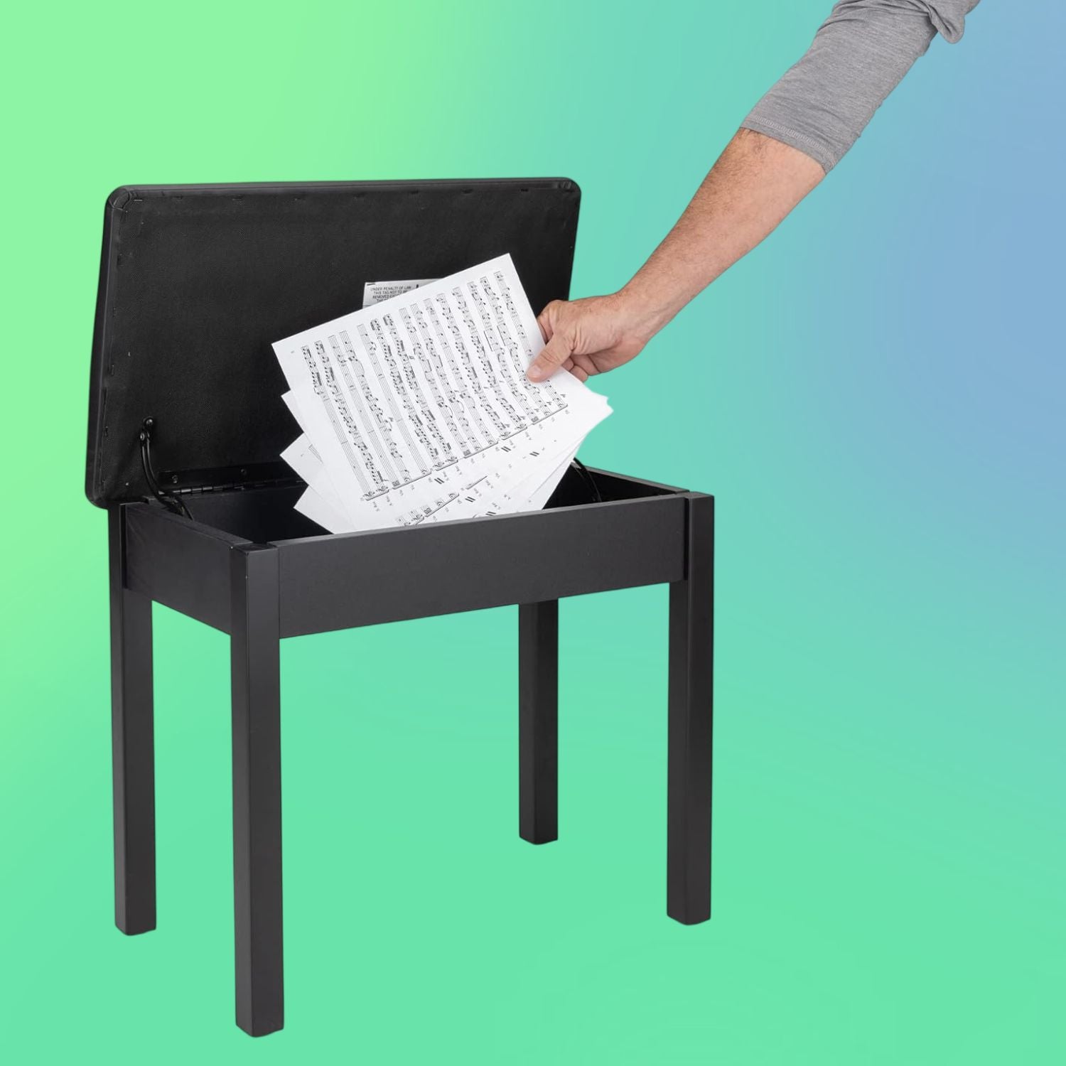 Angled view of On-Stage Flip-Top Keyboard/Piano Bench with arm putting sheet music inside the lid on green and blue background