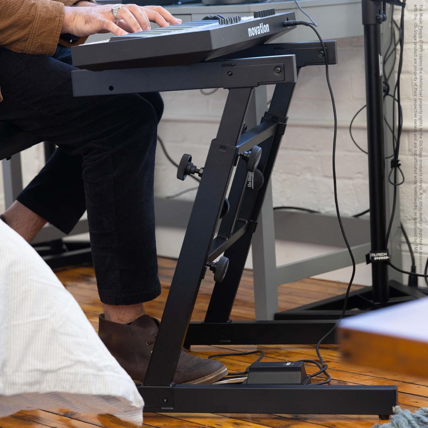 Side view of On-Stage Folding-Z Keyboard Stand with keyboard mounted and keyboardist playing in studio