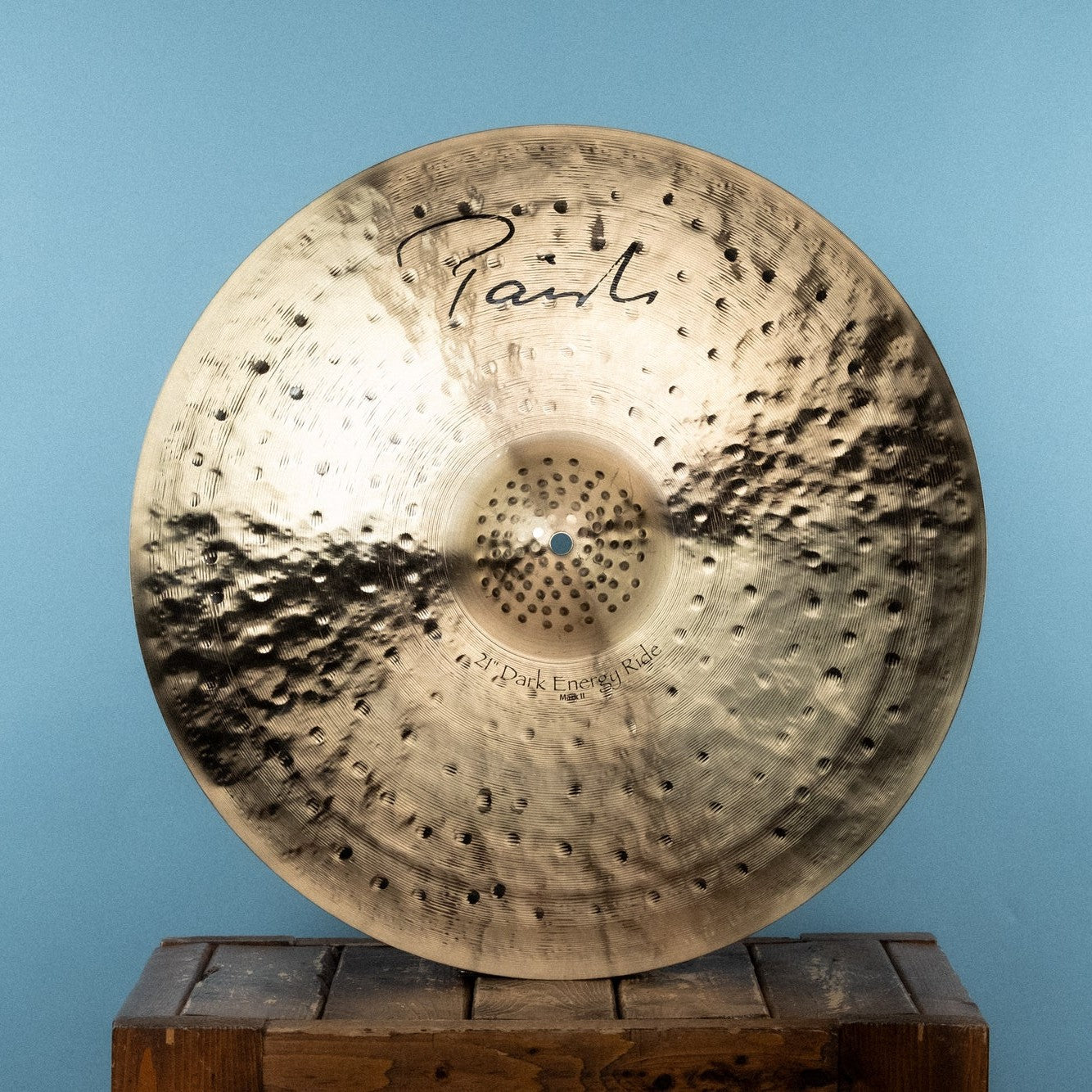 Front view of Paiste 21" Signature Dark Energy Ride Mark II Cymbal on wooden crate with blue background