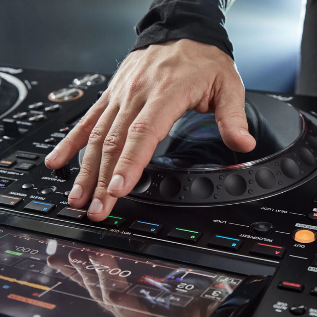 Hand operating a DJ turntable mixer with a blurred background