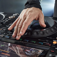 Hand operating a DJ turntable mixer with a blurred background
