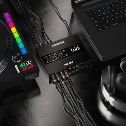 Angled view of Reloop Flux 6x6 In/Out USB-C DVS Interface for Serato DJ Pro with laptop, headphones, and turntable connected to it in studio