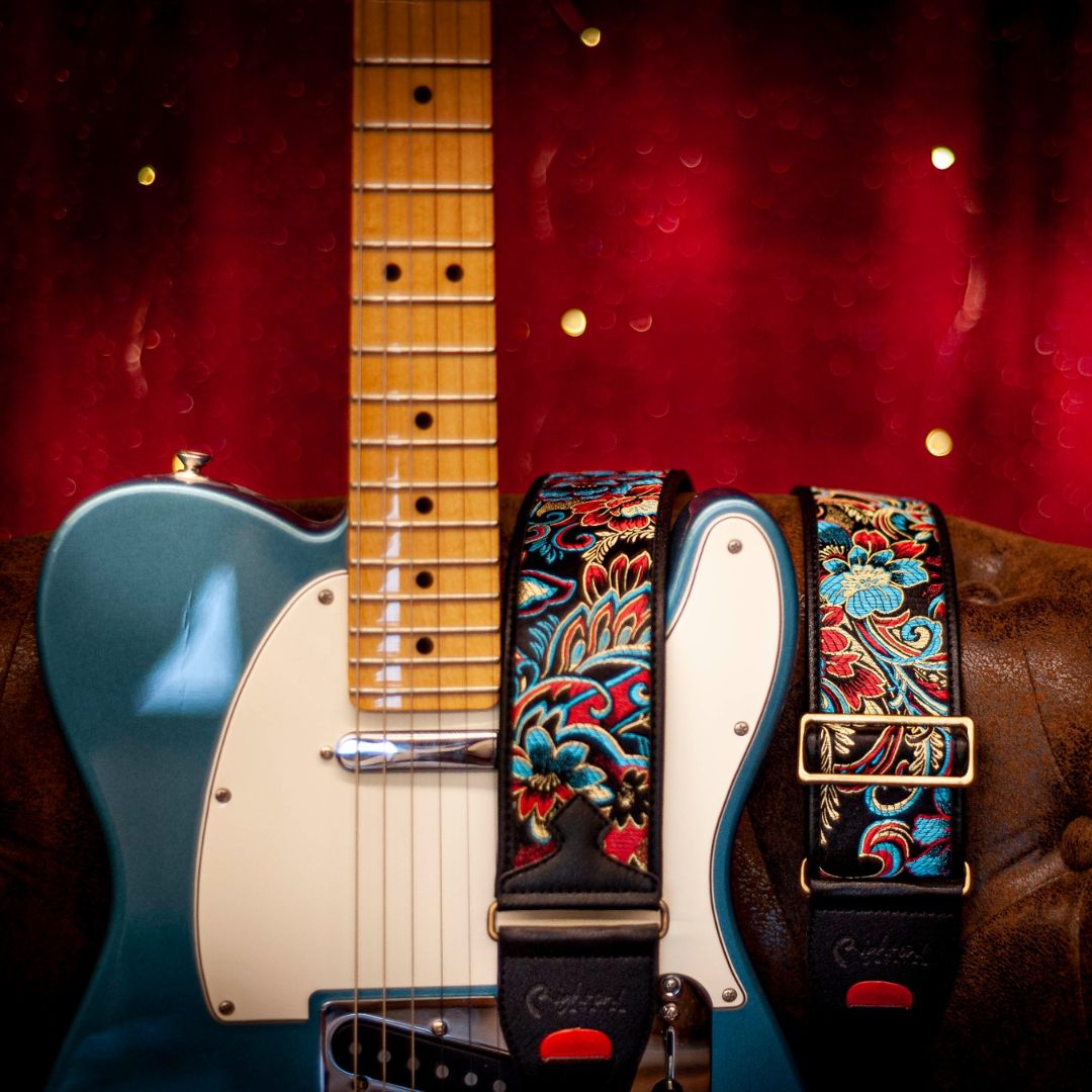 RightOn Beppu II Guitar Strap hung around brown couch and guitar with red background