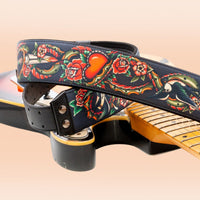 Close up view of RightOn Tattoo Guitar Strap on top of guitar on peach background