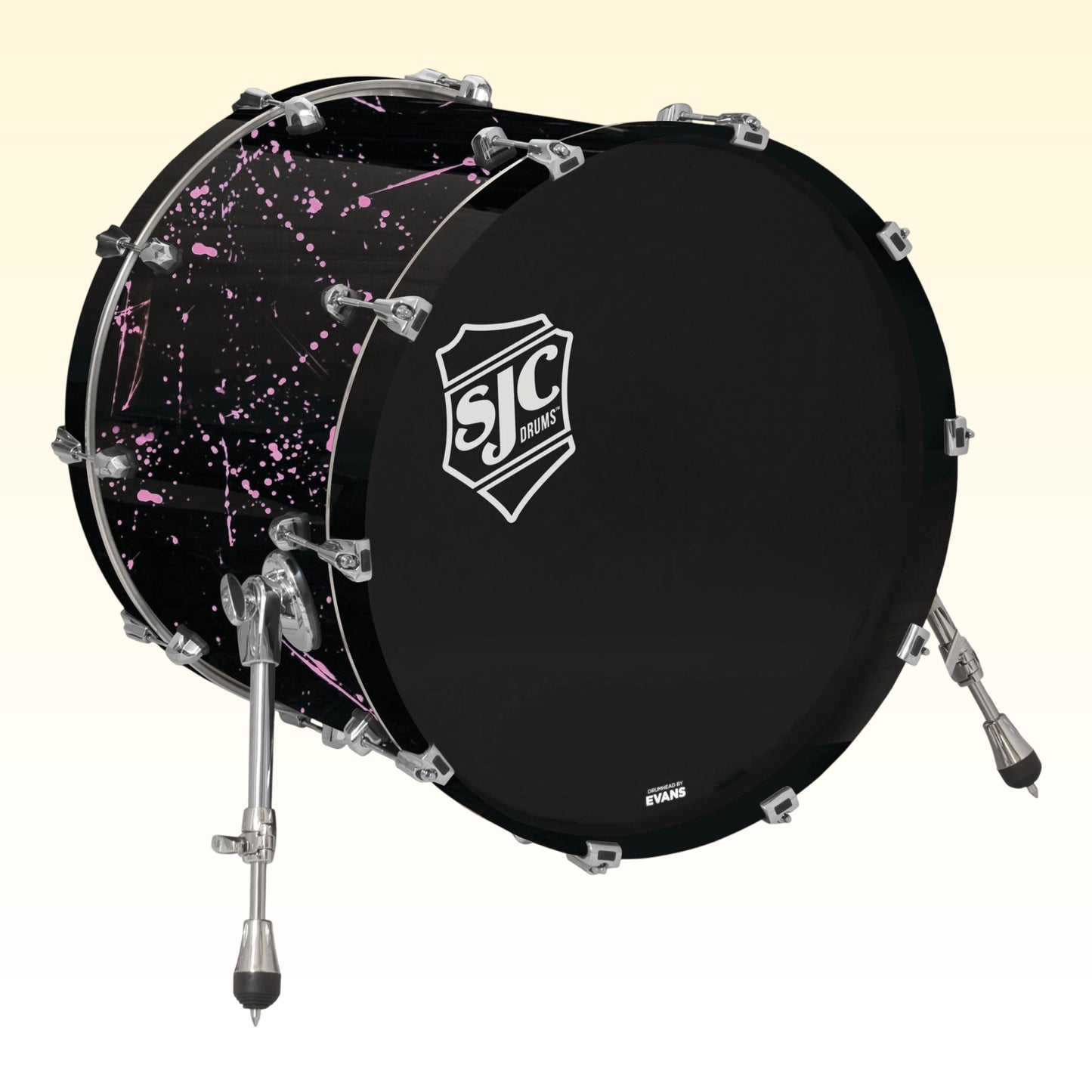 Angled view of SJC Drums Navigator 18" x 22" Bass Drum Black with Pink Splatter on yellow background