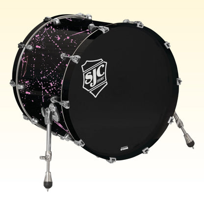 Angled view of SJC Drums Navigator 18" x 22" Bass Drum Black with Pink Splatter on yellow background
