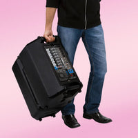 Person holding a large black electronic equipment case against a pink background