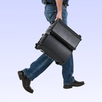 Person carrying a large black toolbox against a light blue background