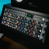 Multiple Solid State Logic Revival 4000 Analog Channel Strips in rack with other rack effects and a studio monitor on top of it