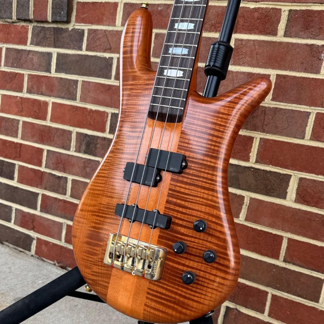 Angled close up front view of Spector Euro 4 DW Doug Wimbish Signature Bass Guitar Amber Stain Gloss with brickwall background