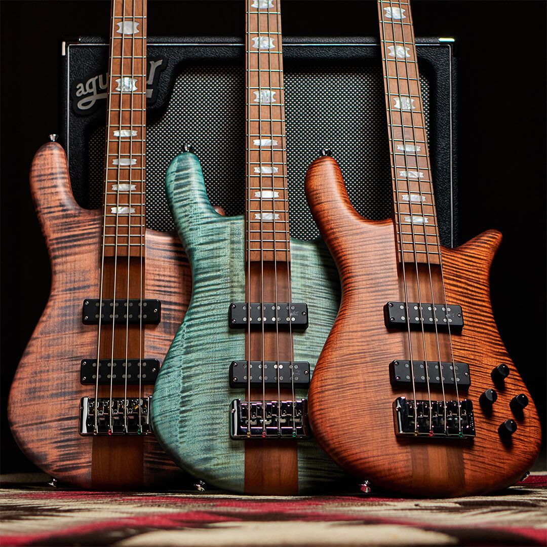 Close up front view of Spector Euro 4 RST Bass Guitar Turquoise Tide Matte, Sienna Stain Matte, and Sundown Glow Matte leaning on amplifier in studio