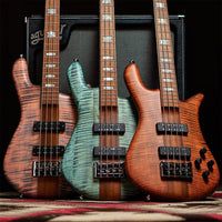 Close up front view of Spector Euro 4 RST Bass Guitar Turquoise Tide Matte, Sienna Stain Matte, and Sundown Glow Matte leaning on amplifier in studio