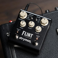 Angled front view of Strymon Flint V2 on top of an amp with wooden floor background