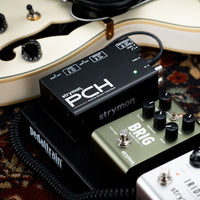 Top view of Strymon PCH beside other pedals on pedal board with guitar on the side