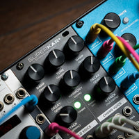 Close up view of Strymon SuperKar+ 32 Voice String Synthesis Eurorack Module on rack with other modules beside it on wooden surface