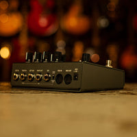 Angled rear view of Strymon TimeLine Multi Delay Pedal on carpet with blurred guitars in background