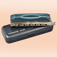 Front view of Suzuki G-48 Chromatic Gregoire Maret Signature Harmonica resting on top of its carrying case on orange background