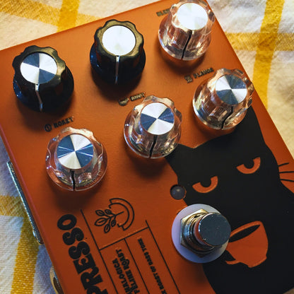 Angled close up view of TONECAT BassPresso Preamp for Bass Pedal on beige cloth with yellow stripes
