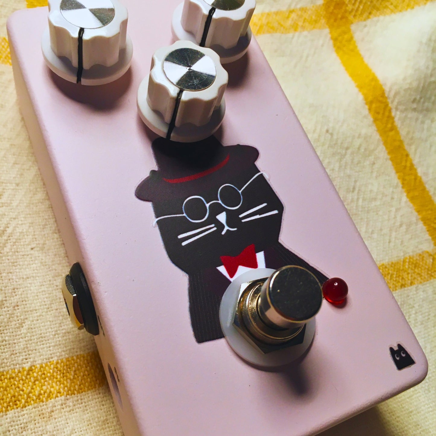 Close up angled view of TONECAT Hugo Overdrive Pedal on beige cloth with yellow stripes