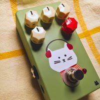 Close up angled view of TONECAT Lola Drive Pedal on beige cloth with yellow stripes