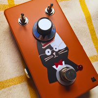 Angled close up view of TONECAT Papa Booster Pedal on beige cloth with yellow stripes