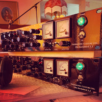 Close up shot of two rackmount effects stacked on top of each other on top of wooden table with a studio background