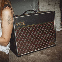 Angled front view of Vox AC10 Hand-Wired Guitar Amplifier with musician leaning on it in gig venue