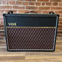 Front view of Vox AC30 Custom Valve Guitar Amplifier Standard on wooden floor with brick wall background