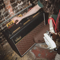 Angled top view of Vox AC30 Hand-Wired Guitar Amplifier with guitarist tweaking the knobs inside gig venue