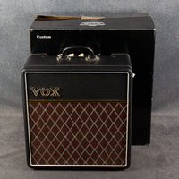 Front view of Vox AC4 Custom 4W 1x12" Combo Amp with its box behind on grey background