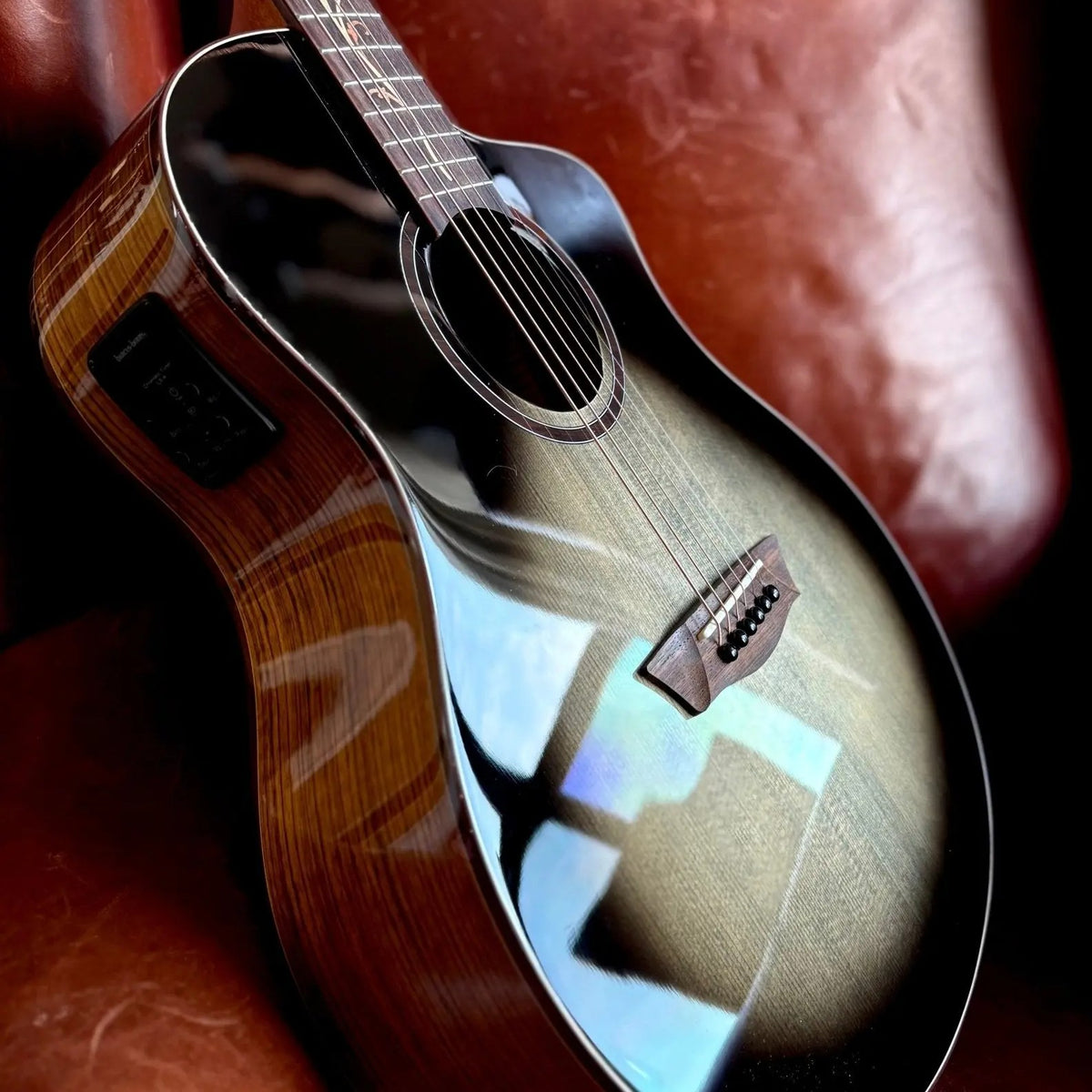 Close up angled view of Washburn VITE S9V Bella Tono Studio Cutaway Acoustic Electric Guitar on red couch