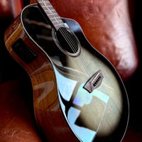 Close up angled view of Washburn VITE S9V Bella Tono Studio Cutaway Acoustic Electric Guitar on red couch