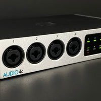 Audio interface with four black jacks and 'AUDIO4C' branding on a dark background